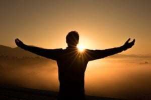 man with outstretched arms in awakening to the sun