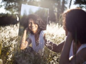 woman holding mirror and smiling at herself