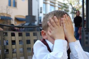 child with hands over face