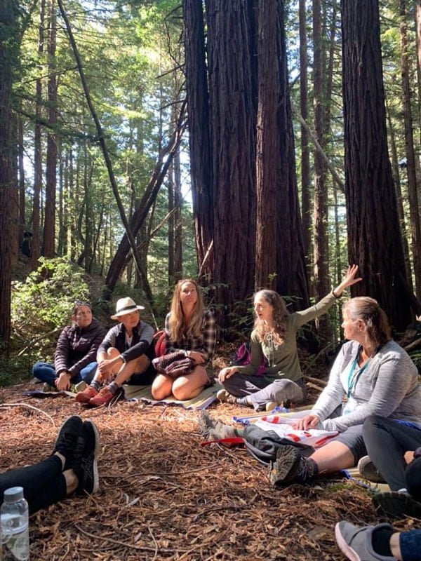 Rev. Connie with ecotherapy group sitting in the forest