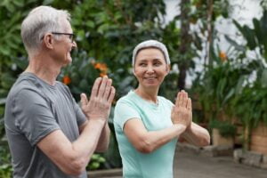 Elderly couple with hands in prayer practicing yoga