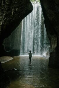 Woman under waterfall cooling herself with water