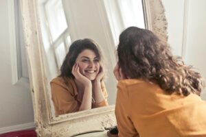 Woman looking in a mirror, smiling, and feeling fine