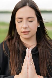 A woman with a peaceful mind, with eyes closed and hands in prayer