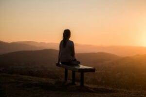 A woman meditating in nature at sunrise or sunset -symbolizing awakening