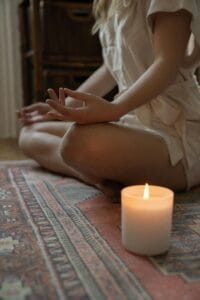 Woman Holding Space Meditating Next to a Burning Candle