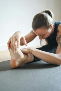 a woman in a forward bend yoga pose, seated yoga stretch, mindful movement practice