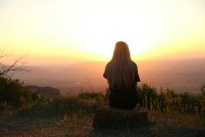 woman in solitude, looking over sunset in the empty mountains for peace and nature