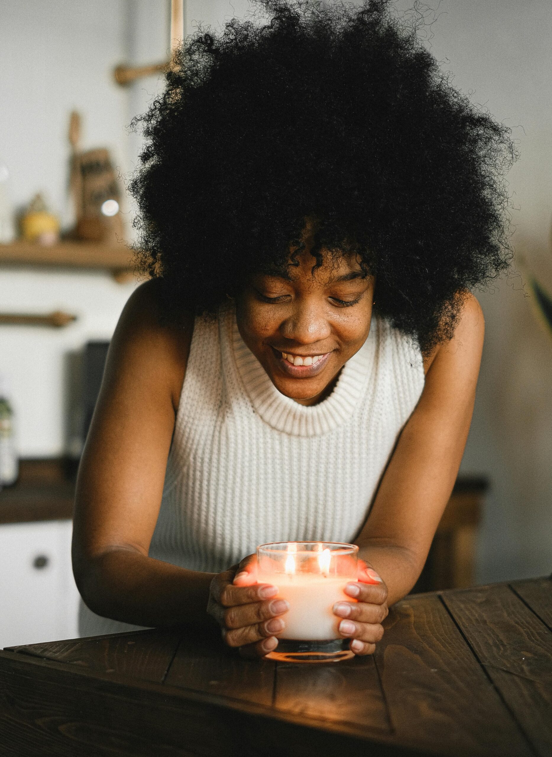 ethnic woman smiling, looking at and holding a candle