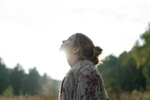 Woman standing in nature looking up with a peaceful gaze